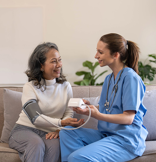 Smiling senior and caregiver sitting together in a cozy living room